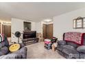 A cluttered living room featuring comfortable seating, neutral carpet, and a functional layout, but with many boxes at 7951 S Estes St, Littleton, CO 80128