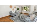 Bright living room with cozy seating arrangement, hardwood floors, decorative rug, and large window at 911 Timber Ct, Longmont, CO 80504