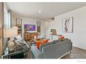 Comfortable living room featuring modern decor, a large TV, and hardwood floors at 9858 Danube Ct, Commerce City, CO 80022