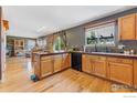 Charming kitchen with natural wood cabinets, stone backsplash, and hardwood floors at 1086 Mockingbird St, Brighton, CO 80601