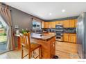Eat-in kitchen featuring stainless steel appliances and a wood center island with seating at 1086 Mockingbird St, Brighton, CO 80601