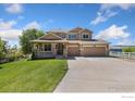 Charming home showcasing a covered porch with stone pillars, three-car garage, and a well-manicured lawn at 10970 E 150Th Pl, Brighton, CO 80602