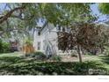 Side view of a charming two-story home featuring a well-manicured lawn, mature trees and fenced area at 1315 Gaylord St, Denver, CO 80206