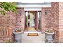 Inviting front entryway with brick facade, potted flowers, and a clear view into the foyer at 1401 Clover Creek Dr, Longmont, CO 80503