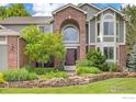Beautiful home with well-manicured lawn, landscaped flower beds, and a stone retaining wall at 1401 Clover Creek Dr, Longmont, CO 80503