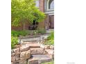 Landscaped yard featuring stone steps, a flower garden, and a mature tree near the front door at 1401 Clover Creek Dr, Longmont, CO 80503
