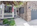 Inviting front porch and door area with a charming brick design and views to an attached two-car garage at 2085 Tundra Cir, Erie, CO 80516