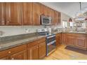 Spacious kitchen with warm wood cabinetry, granite countertops, modern appliances and hardwood floors at 2085 Tundra Cir, Erie, CO 80516