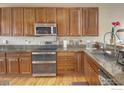 Open kitchen with stainless appliances, granite counters, and wood cabinets offering style and functionality at 2085 Tundra Cir, Erie, CO 80516