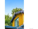 Close-up of the charming architectural details of the yellow house with intricate trim and a blue window frame at 2320 22Nd St, Boulder, CO 80304