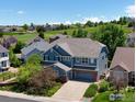 Spacious two-story home with blue siding, a well-manicured lawn, and a large driveway at 23570 E Holly Hills Way, Parker, CO 80138