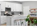 Modern kitchen with white cabinetry, stainless steel appliances, and a breakfast bar perfect for casual dining at 308 Fickel Farm Trl, Berthoud, CO 80513