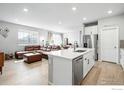 Open-concept kitchen featuring a quartz island, stainless steel appliances, and hardwood floors leading to the living area at 308 Fickel Farm Trl, Berthoud, CO 80513