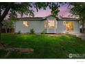 Back exterior showcasing a well-maintained lawn, bay window, and sliding glass door at 3557 Settler Ridge Dr, Mead, CO 80542