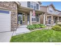 Inviting front porch with stone accents, green shutters and American flag at 853 Jenny Ln, Berthoud, CO 80513