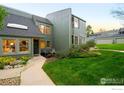 Two-story townhome with lush green lawn, manicured flower beds, and gray chairs on the front porch at 93 Benthaven Pl, Boulder, CO 80305
