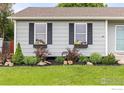 Landscaped front of the home features lush green grass, garden beds, and black shutters with flower boxes at 13441 Sheridan Blvd, Broomfield, CO 80020