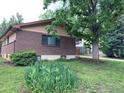 Brick exterior with a large tree and flower garden at 3490 Emerson Ave, Boulder, CO 80305