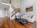 Bright living room featuring gleaming hardwood floors, open staircase, and comfortable seating arrangement at 4795 Raven Run, Broomfield, CO 80023