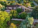 Aerial view of a custom home featuring mature landscaping, a large deck, and an attached garage at 495 S Cedar Brook Rd, Boulder, CO 80304