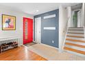 Inviting entryway featuring a striking red door, stylish coat racks, and hardwood floors leading to the upper level at 5355 Kewanee Dr, Boulder, CO 80303
