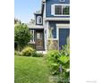 Close-up of the blue two-story home featuring a well-manicured lawn and landscaping at 823 Timothy Dr, Longmont, CO 80503