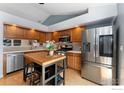 Modern kitchen featuring stainless steel appliances, center island with seating, and wood cabinetry at 8391 Sunnyside Pl, Highlands Ranch, CO 80126