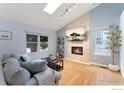 Bright living room with a fireplace, a large window, skylight, and a comfortable couch at 8391 Sunnyside Pl, Highlands Ranch, CO 80126