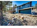 Exterior side view of a home with a stone chimney, wooden deck, and natural rock landscaping at 8483 Thunderhead Dr, Boulder, CO 80302