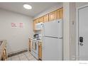 Well-lit kitchen with white appliances, wooden cabinets, and tiled floor at 1065 University Ave # 121, Boulder, CO 80302