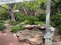 Serene backyard featuring a rock water feature, mature trees and a brick patio at 1279 Cressida Ct, Lafayette, CO 80026
