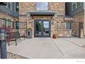 Close-up of the building entrance showcasing a stone facade, double doors, and a bench for residents and guests at 13598 Via Varra # 404, Broomfield, CO 80020