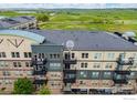 Multi-story condo building featuring a private balcony, stone accents, and a view of grassy fields and a distant lake at 13598 Via Varra # 404, Broomfield, CO 80020