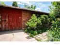 Exterior view of a brick garage with a large red door, surrounded by greenery at 1380 Ithaca Dr, Boulder, CO 80305