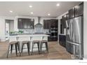 Stylish kitchen featuring stainless appliances, a central island with bar stools, and sleek dark cabinetry at 1677 Meagan Way, Erie, CO 80516