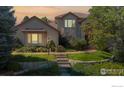 Inviting two-story home with stone accents, lush lawn and garden, and well-lit walkway at 1977 Champions Cir, Castle Rock, CO 80104