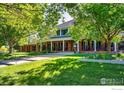 Two-story brick home with a covered front porch and lush lawn, perfect for enjoying the outdoors at 20360 County Road 3, Berthoud, CO 80513