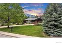Beautiful home with lush green lawn and mature trees, with a mountain view in the background at 205 Lipan Way, Boulder, CO 80303