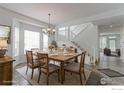 Inviting dining room with a rustic wooden table, chandelier, and access to the staircase and hall at 2631 E 136Th Pl, Thornton, CO 80602