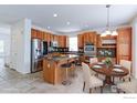 Bright kitchen features wood cabinetry, stainless steel appliances, island with seating, and an adjacent dining area at 2631 E 136Th Pl, Thornton, CO 80602