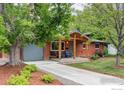 Charming brick home featuring a covered front porch with chairs, mature trees and an attached garage at 3445 Martin Dr, Boulder, CO 80305