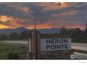 Heron Pointe sign at sunset with a dramatic sky and mountains in the background at 3572 Lissa Dr, Berthoud, CO 80513