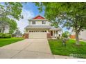 Charming two-story home with a two car garage, lush green lawn and mature trees at 5023 Goshawk Ct, Brighton, CO 80601