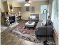 Cozy living room featuring a stone fireplace, plush seating, and a patterned area rug at 804 Nelson Park Ln, Longmont, CO 80503