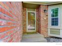 Close-up of a brick facade showcasing the home's entrance, complete with a glass storm door and welcome mat at 11535 Briarwood Ln, Parker, CO 80138