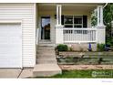 Inviting covered front porch with white columns, decorative railing, and flower beds at 1309 Red Mountain Dr, Longmont, CO 80504