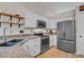 Well-lit kitchen features stainless steel appliances, granite countertops, and floating wood shelves at 1309 Red Mountain Dr, Longmont, CO 80504