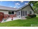 A peaceful backyard with a screened-in porch, patio, colorful flowers, and green grass, perfect for relaxing outdoors at 1515 Tulip Ct, Longmont, CO 80501