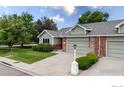 Well-maintained home with green siding, brick detail, driveway, and landscaped front yard under a blue sky at 1515 Tulip Ct, Longmont, CO 80501