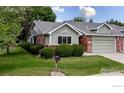 A charming single-story home with green siding, brick accents, and manicured lawn under a sunny blue sky at 1515 Tulip Ct, Longmont, CO 80501